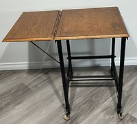 Full view of the Mid-Century Modern wooden secretary typewriter table showing the fold-down side panel extended, metal legs, and caster wheels.
