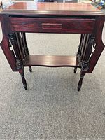 Front view of the antique wooden occasional table showing drawer, drop leaves, and turned legs.