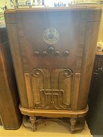 Full view of antique Westinghouse floor radio cabinet showing wood grain, control knobs, decorative metal grille, and legs.
