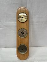 Full view of the wooden plank with three round metal-cased dials for weather measurements.