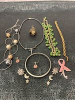 Full view of costume jewelry pieces displayed on black mat including necklaces, ring, earrings, pin, and bracelets.