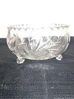 Side view of heavy crystal bowl showing pinwheel and floral cut patterns and three rounded feet