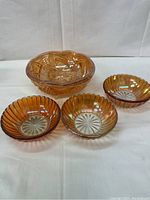 Front view of all four carnival glass bowls showing the large footed bowl and three smaller ribbed bowls.