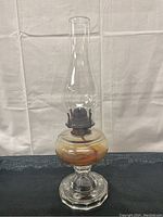 Full view of the vintage hurricane lamp showing the glass chimney, brown reservoir and etched clear glass base.