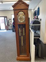 Full view of the grandfather clock with wooden case and visible weights inside.