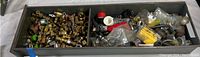 Wide view of metal tray containing assorted plumbing parts and fittings including valves, connectors, adapters and installation components, some packaged in plastic bags.
