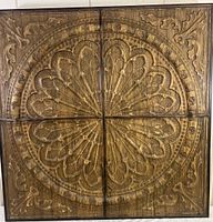 Full view of the four-panel composite wood carving artwork showing the circular floral design with leaf elements on each corner.
