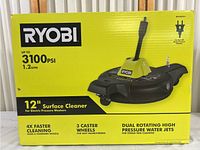 Front of the yellow and black box showing Ryobi brand, product photo of the surface cleaner, and text with specifications including 3100 PSI, 1.2 GPM, 12 inch size, 4x faster cleaning, 3 caster wheels, dual rotating jets.