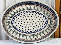 Top view of the oval ceramic dish showing the star pattern in the center, pine tree motif around the edge, and decorative border.