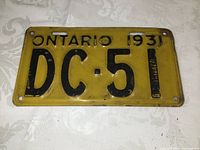 Front view of vintage 1931 Ontario license plate with yellow background and black characters 'DC-51'.