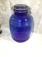 Front view of cobalt blue glass cookie jar showing embossed text and metal clasp lid.