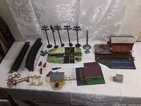 Overview of train track sections, signal poles, buildings, and accessories arranged on a table showing scale and condition
