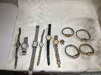 All ten watches laid out showing variety of bands and face shapes, mostly metal bands with one leather.