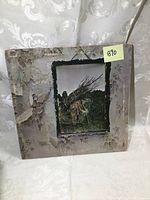 Front cover of the Led Zeppelin IV vinyl album showing iconic image of an elderly man carrying sticks, with peeled and worn edges.