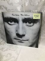 Front cover of Phil Collins Face Value album showing close-up black and white photo of his face with album and artist name handwritten on top.