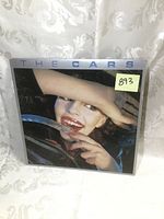 Front cover of The Cars LP album showing a close-up of a smiling woman partially covering her eyes with her hand.