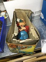 Vintage tin toy bartender displayed with its original box, showing the figure standing and holding a bottle.