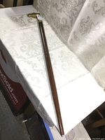 Full view of the wooden cane laid on fabric, showing overall length and shaft material.