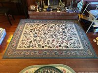 Full view of the Catherine Collection area rug showing the entire floral patterned surface and border on a wooden floor.