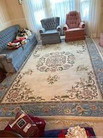 Full view of the floral medallion area rug in a living room setting with sofa and chairs, highlighting pattern and scale.