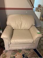 Front view of the beige faux leather armchair, showing padded arms and backrest.