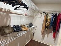 Wide shot of several handbags, scarves, and boots arranged on shelving and hanging from hooks on the wall in a closet space.