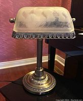 Full view of bankers lamp showing frosted etched glass shade, metal brackets and detailed metal base