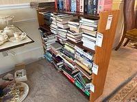 Wooden bookshelf filled with books and some VHS tapes on top. Shown with side angle and measuring label visible.