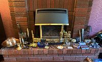 Wide shot of fireplace mantel with assortment of candle votives, holders, candelabra, and candles arranged along the hearth