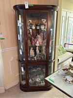 Front and side view of tall wooden display cabinet with glass doors, showing contents inside excluded from sale.