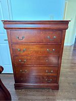 Front view of the dresser showing five drawers and metal handles on all but one drawer.