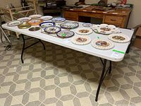 Photo showing folding table fully opened with decorative plates on top, illustrating the table surface and legs.