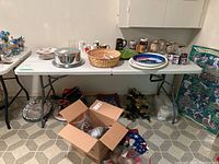 White folding table with resin top and metal legs set up in basement with various household items on and around it.