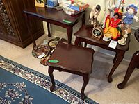 Three wooden nesting tables in dark brown finish shown stacked and side by side on carpeted floor, with surrounding items not included.