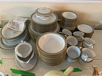 Full arrangement of Noritake Nitto Ware 2006 china on table, showing stacks of dinner plates, bowls, cups, saucers, and gravy boat.