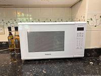 Front view of white Panasonic microwave on kitchen counter showing vents and door window.