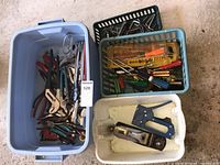 Overall bin with assorted hand tools including wrenches, pliers, screwdrivers, and staplers in plastic storage bins.