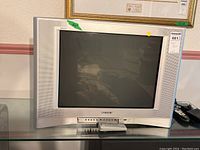 Full front view of the silver Sony Wega television showing the screen, speaker grills, and control buttons with remote placed in front.