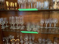 Shelf view showing a variety of stemware and glassware including gold accented goblets, crystal-cut glasses, and tumblers.