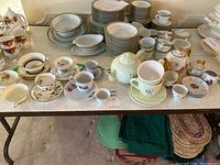 Overview of assorted teapots, teacups, and plates on a table showing variety and quantity.