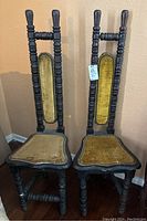 Front view of two vintage carved wooden chairs with mustard yellow velvet upholstery and decorative brads, showing condition and design.