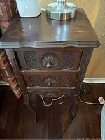 First photo of one antique dark wood accent table showing top surface with scratches, two front drawers with ornate carved design and original hardware, cabriole legs. Shows peeling on edges and typical wear for restoration.