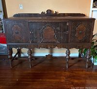 Front view of antique wood buffet cabinet showing central drawers and side doors with carved panel details and metal pulls.