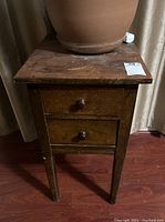 Front view of the antique wooden table showing two drawers and top surface with visible wear and scratches.