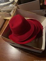 Four red felt ladies hats stacked in cardboard box, showing condition and style