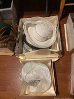 Photo showing multiple white and black hats in a box, including lace and netting details