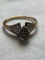 Front view of vintage ladies 10K gold ring with cluster of small stones in flower-like setting and triangular textured accents on band sides.