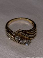 Front view of the gold ring showing three diamonds embedded in the setting and decorative lines on band.