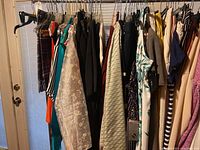View of ladies clothing rack showing multiple dresses and other garments hanging on hangers.