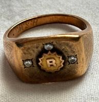 Front view showing gold 'R' monogram surrounded by three small stones and textured ring face.